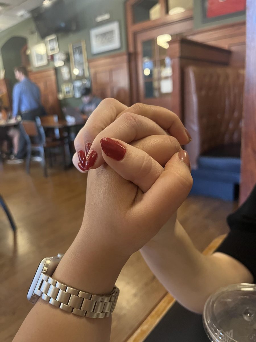 Two students clasp hands in a Holy Grounds booth.